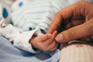 photo - Adult Hand Holding Infant Hand