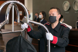 photo - Bellboy Working at a Hotel, Wearing a Mask