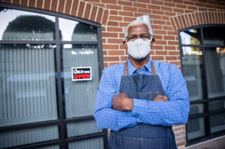 photo - Business Owner Standing Outside with Open Sign on Door