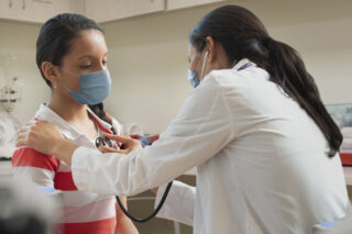 photo - Doctor Listening to Heart of Young Patient in Exam Room