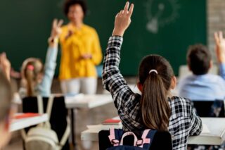 photo - Back View of Student Raising Her Hand in Class