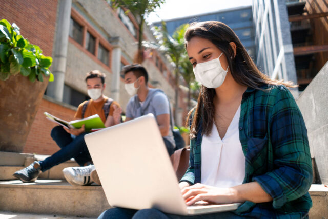 photo - Female student working on a laptop on college campus