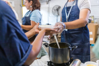 photo - Man handing soup to a woman at a food bank