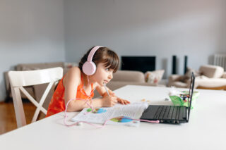 photo - girl wearing headphones and using laptop doing her homework