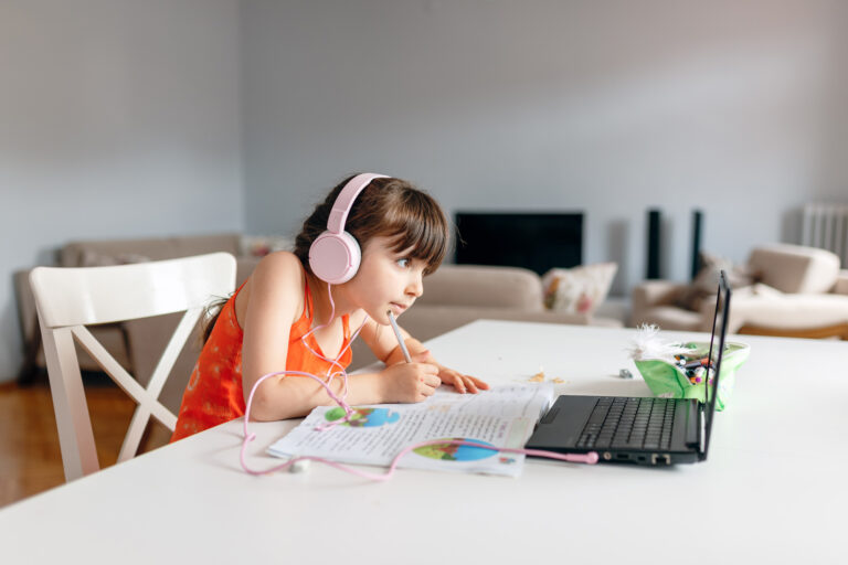 photo - girl wearing headphones and using laptop doing her homework