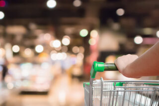 photo - Woman's Hand Pushing Shopping Cart in Grocery Store