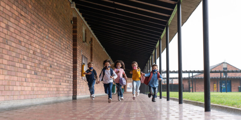 photo - Happy Group of Kids Running at School Wearing Facemasks