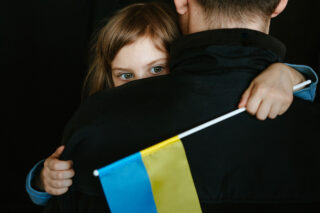 photo - Little Girl Holding Ukrainian Flag and Being Held by her Dad