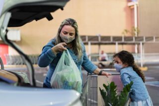 photo - Mom With Daughter Putting Groceries In Car