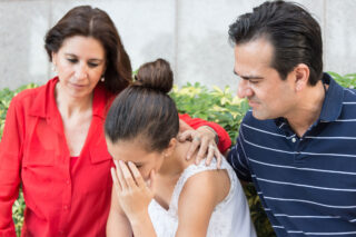 photo - Mother and Father Consoling Sad Daughter