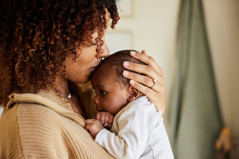 photo - Mother Kissing Forehead of Baby in Her Arms