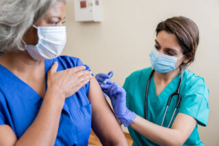 photo - Nurse Vaccinates Senior Healthcare Worker