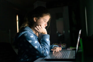 photo - Student working on computer at night