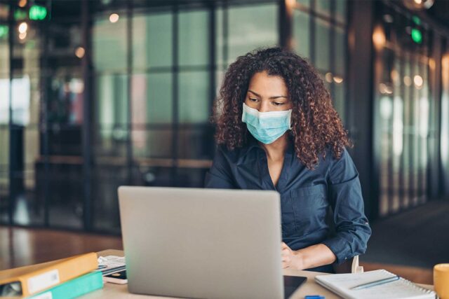 photo - Tech Worker Wearing Mask at Laptop