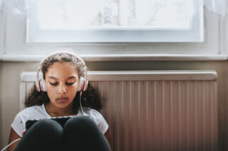 photo - Teenage Girl Listening with Headphones and Looking at Tablet