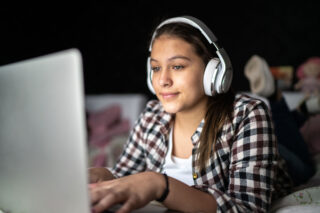 photo - Teenage Girl Using Laptop and Wearing Headphones at Home