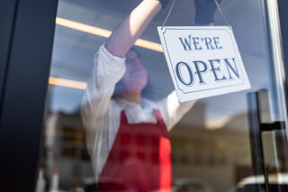 photo - Woman Placing Open Sign in Storefront