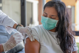 photo - Woman receiving COVID-19 vaccine at home