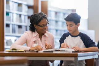 photo - Woman Tutoring Preteen Boy in School Library