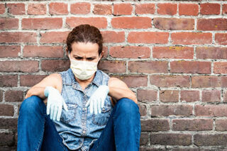 photo - Woman Wearing Protective Mask and Gloves, Looking Down and Sitting on Ground