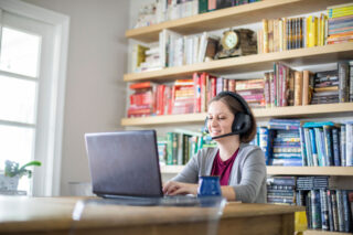 photo - Woman Working from Home Using Laptop and Wearing Headphones