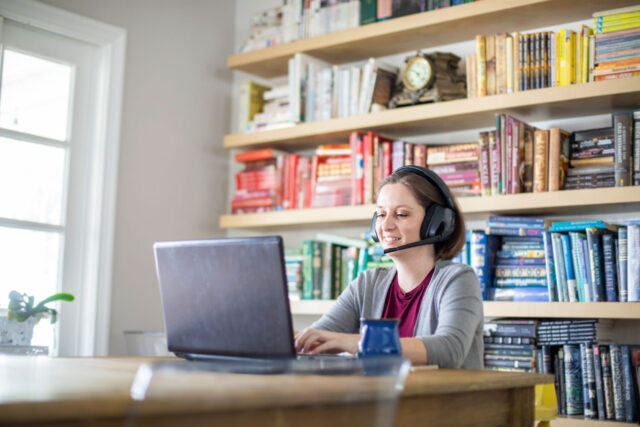 photo - Woman Working from Home Using Laptop and Wearing Headphones